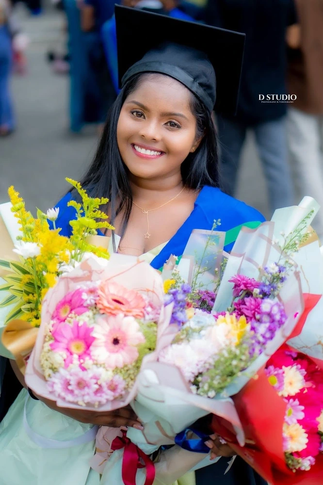 A graduate holding colourful bouquets, photographed by D Studio